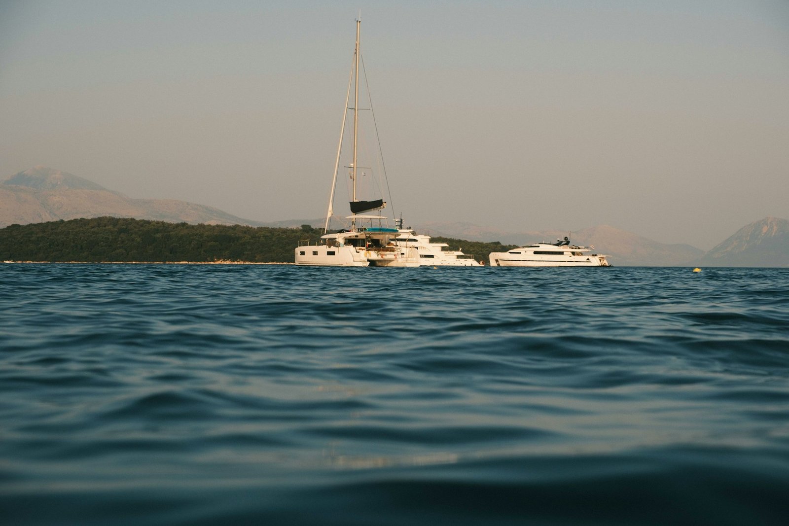 Sailboats anchored beside a sunlit island